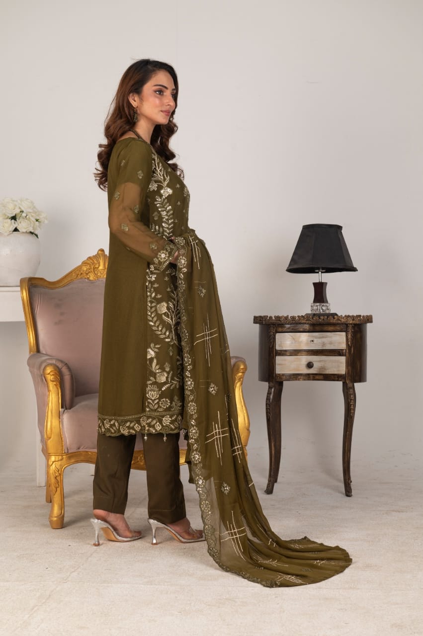 Woman in a green embroidered outfit standing in side pose