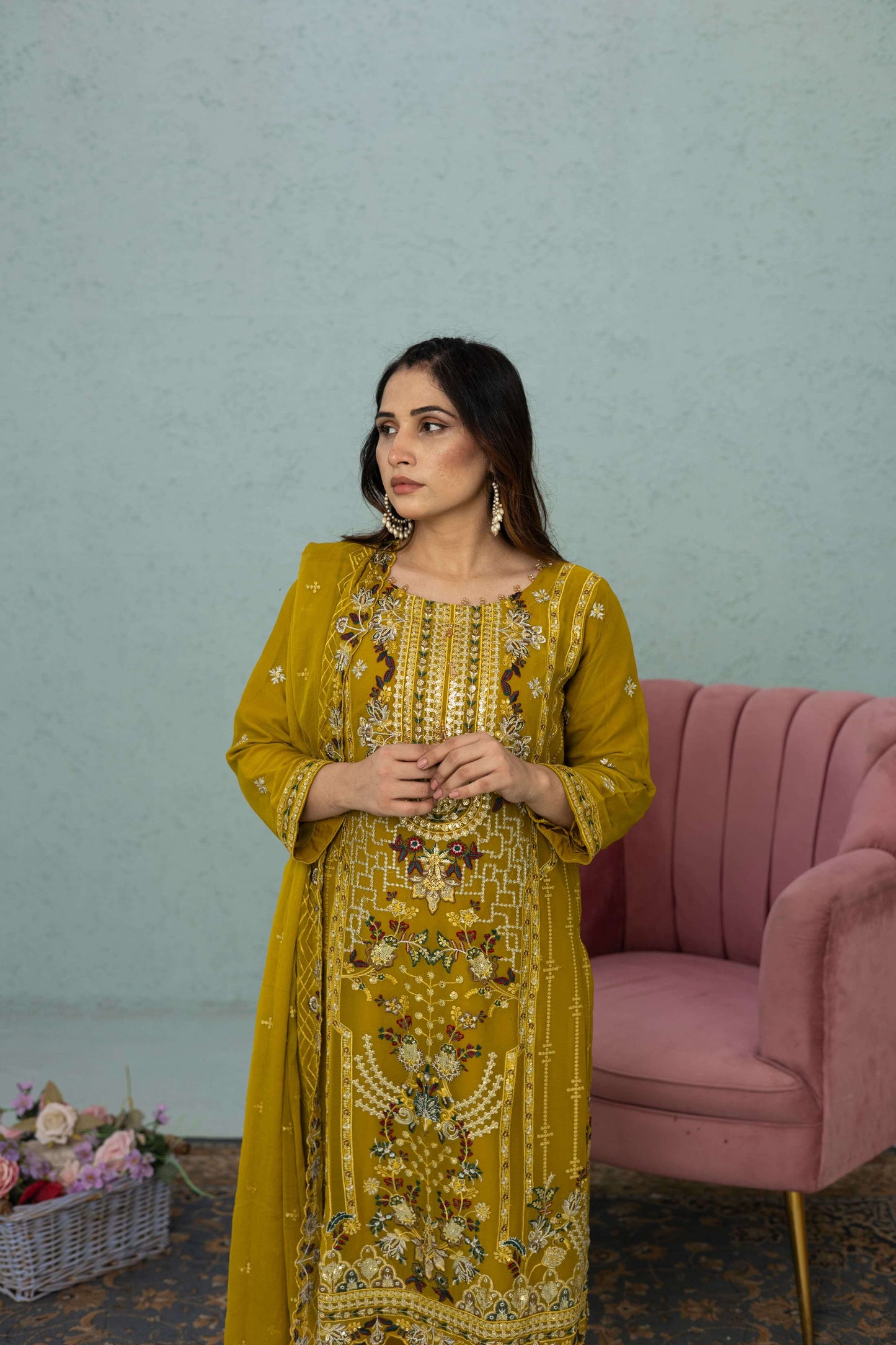 Woman in a light mustard traditional chiffon shalwar kameez outfit standing in a room front picture