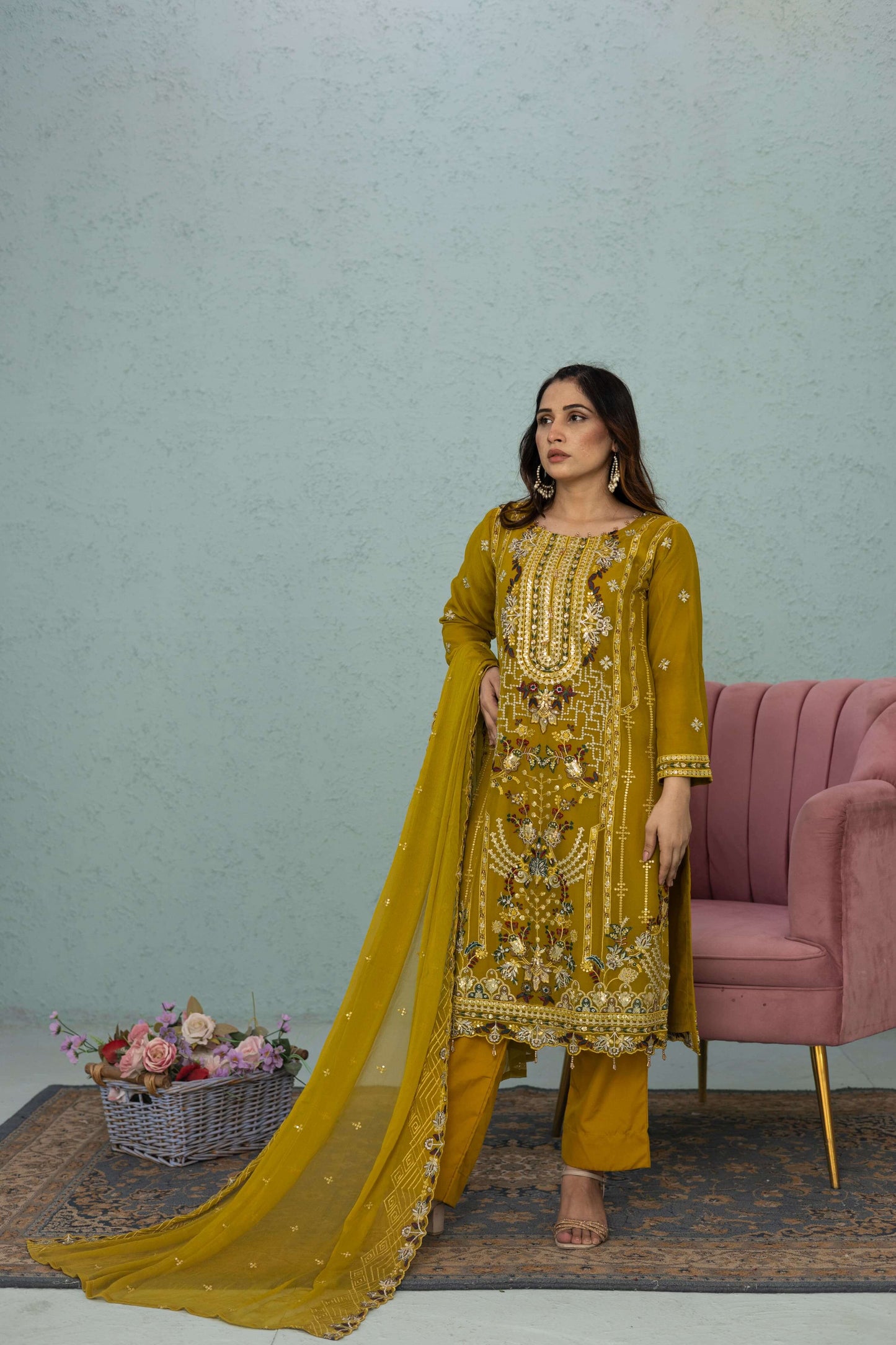 Woman in a light mustard traditional chiffon shalwar kameez outfit standing in a room