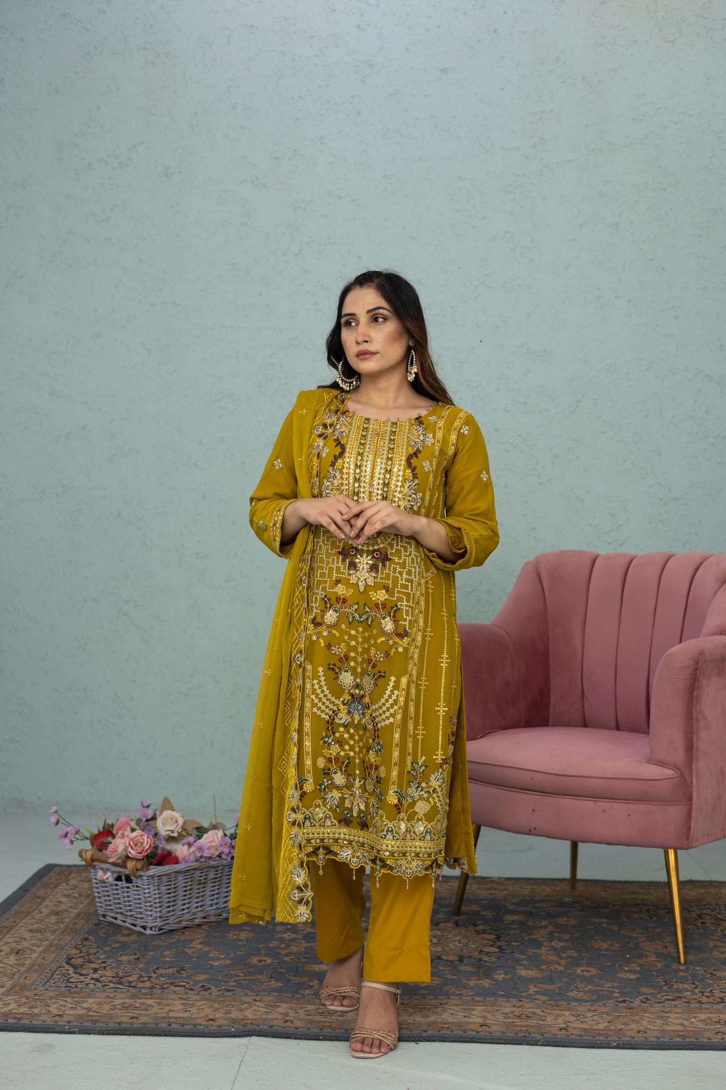Woman in a light mustard traditional chiffon shalwar kameez outfit standing in a room full picture