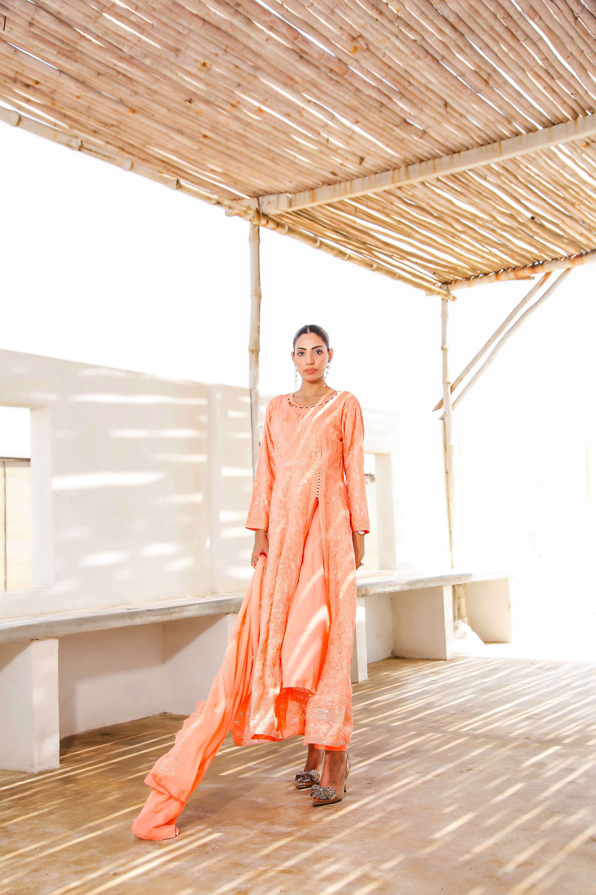 Model twirling in melon chiffon frock