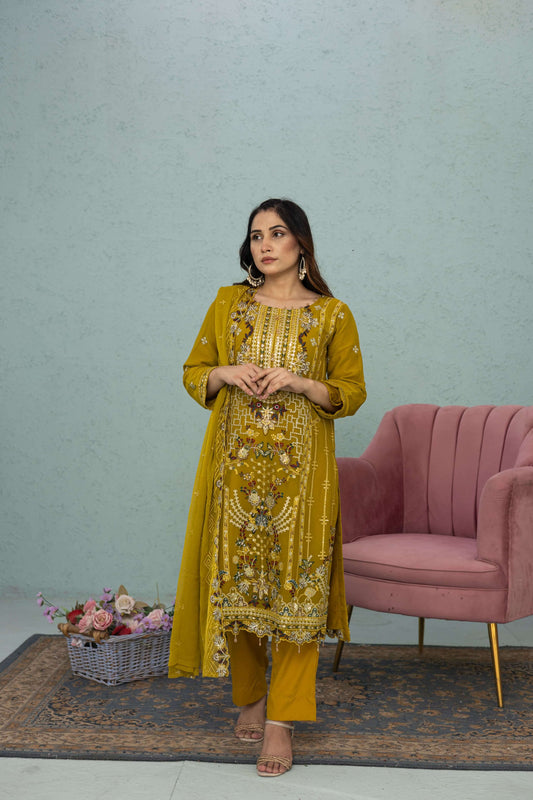 Woman in a light mustard traditional chiffon shalwar kameez outfit standing in a room full picture