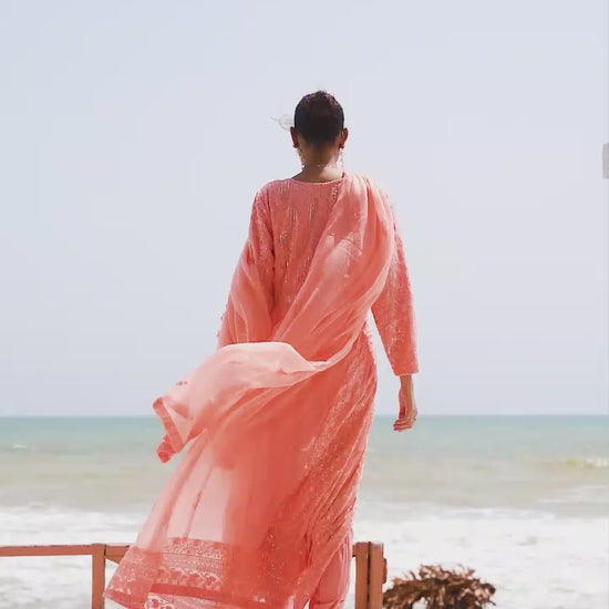 Model twirling in melon chiffon Anarkali frock, highlighting flowy silhouette, embroidery details, and soft movement of the fabric.