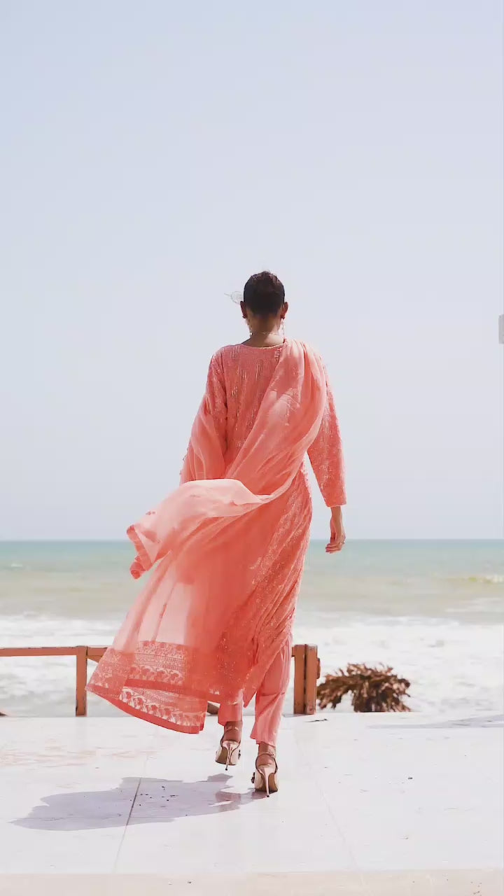 Model twirling in melon chiffon Anarkali frock, highlighting flowy silhouette, embroidery details, and soft movement of the fabric.