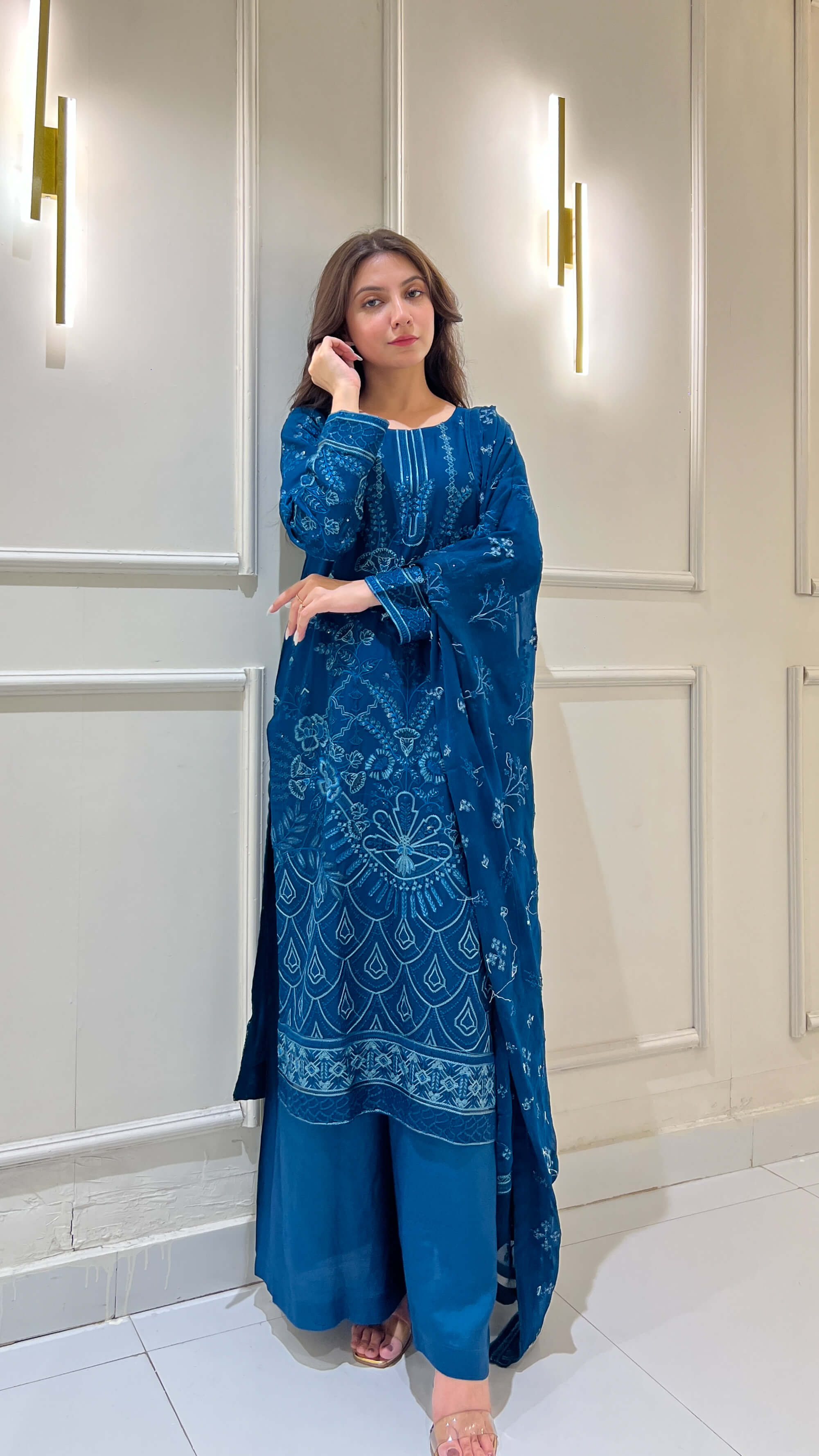 Woman in traditional pose wearing peacock blue embroidered outfit in video